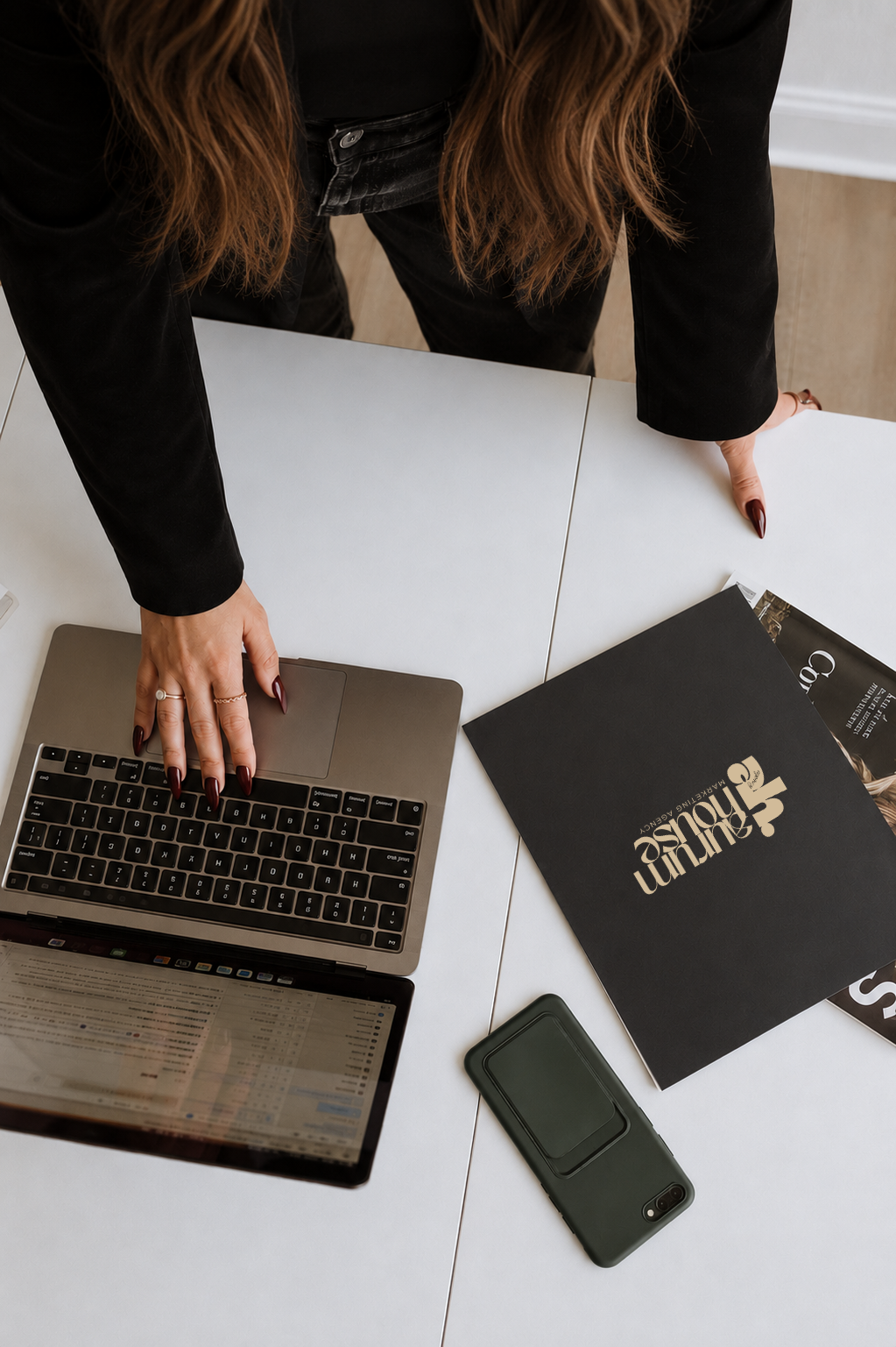 Aurum House branded workspace with laptop, phone, and printed materials