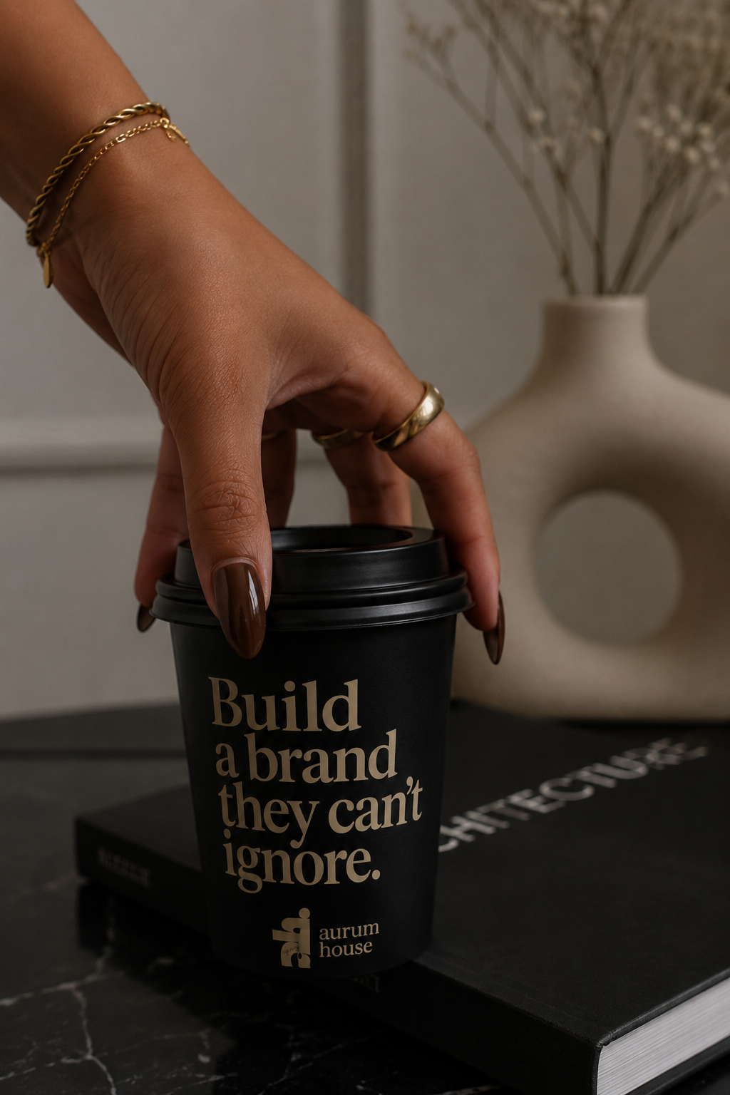 Aurum House branded coffee cup reading 'Build a brand they can't ignore' on a marble surface