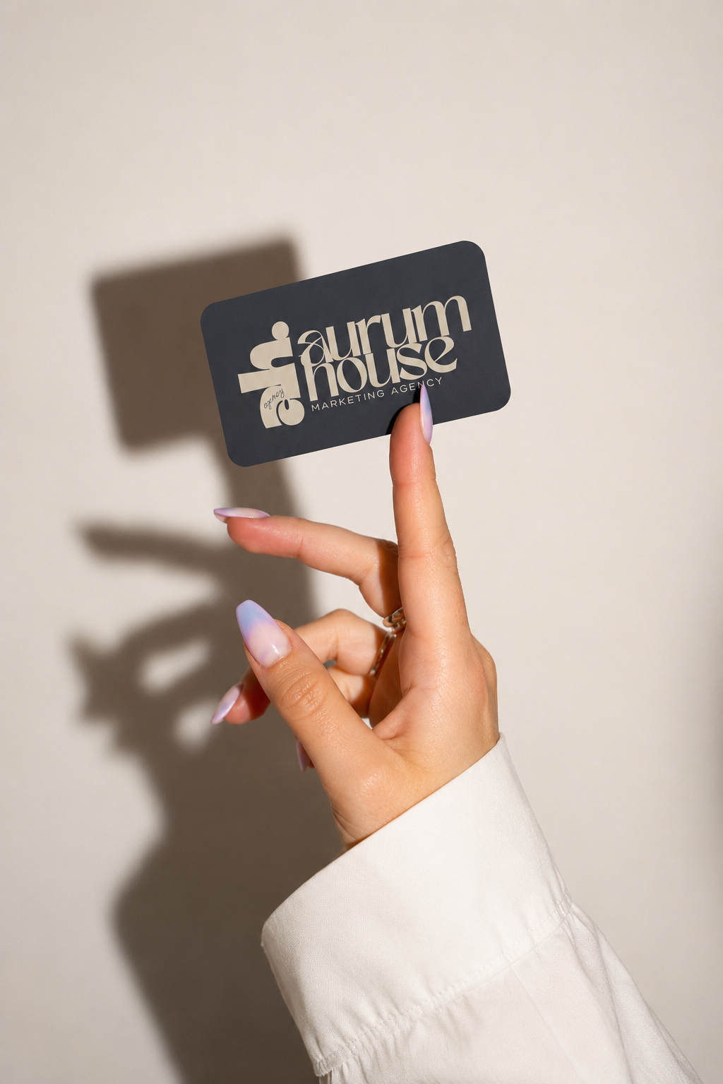 Aurum House business card held against a soft cream wall